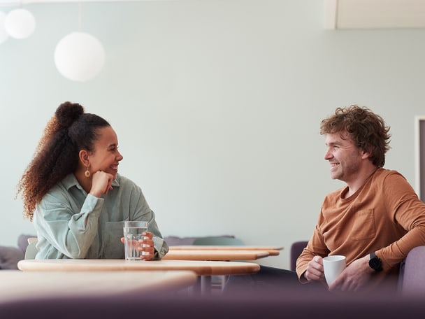 Zwei Menschen sitzen an einem Tisch und trinken Kaffee.
