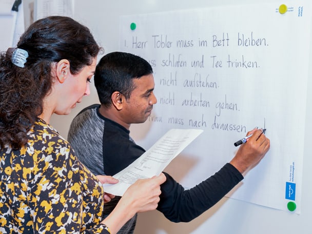 Zwei Menschen schreiben an der Tafel. 