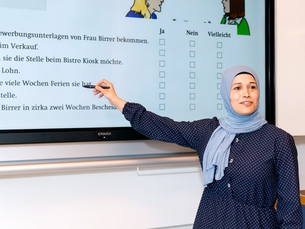 Mensch steht vor einer digitalen Wandtafel. 