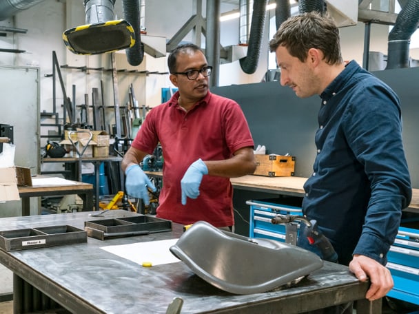 Zwei Menschen stehen in einer Werkstatt.