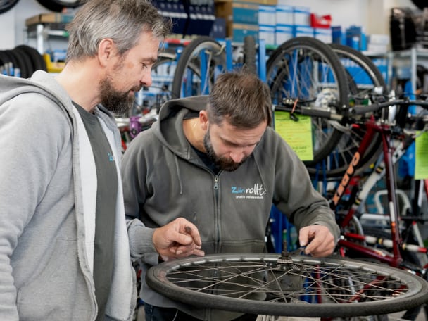 Zwei Menschen reparieren ein Fahrradpneu. 