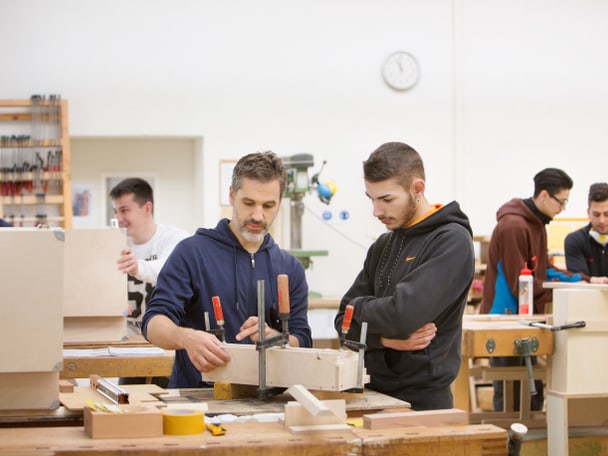 Zwei Menschen arbeiten in einer Holzwerkstatt. 