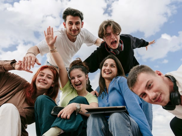 Mehrere Jugendlicher lachen in eine Kamera.