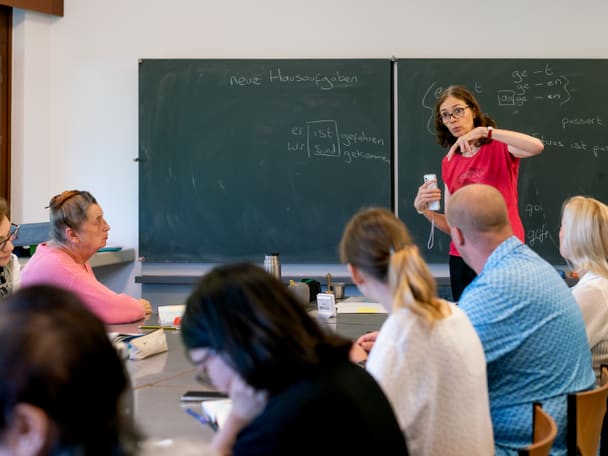 Eine Frau unterrichtet vor einer Klasse. 