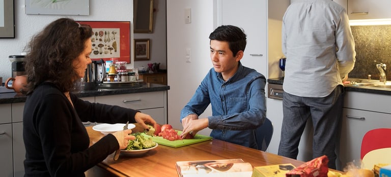 Geflüchtete Person bei Gastfamilie beim Kochen