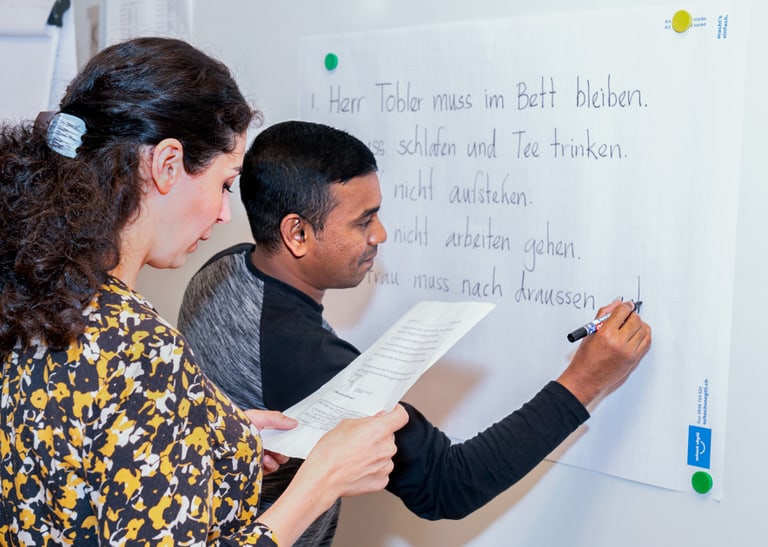 Zwei Menschen schreiben an der Tafel.
