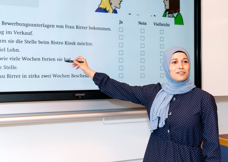 Mensch steht vor einer digitalen Wandtafel. 