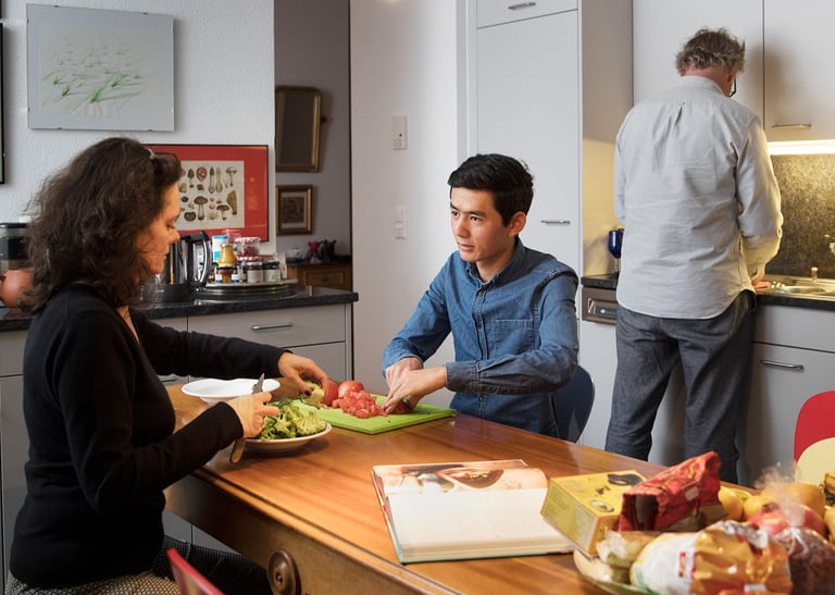 Geflüchtete Person bei Gastfamilie beim Kochen