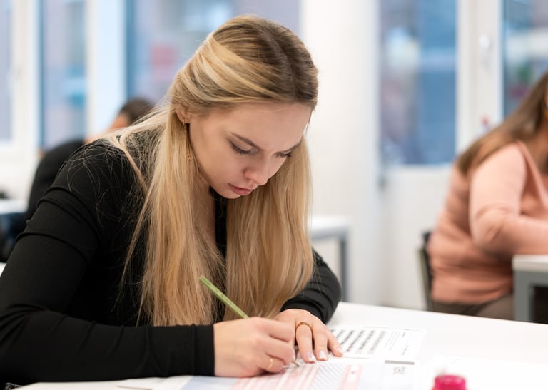 Mensch sitzt am Tisch und schreibt. 
