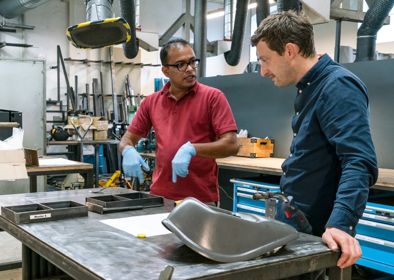 Zwei Menschen stehen in einer Werkstatt.