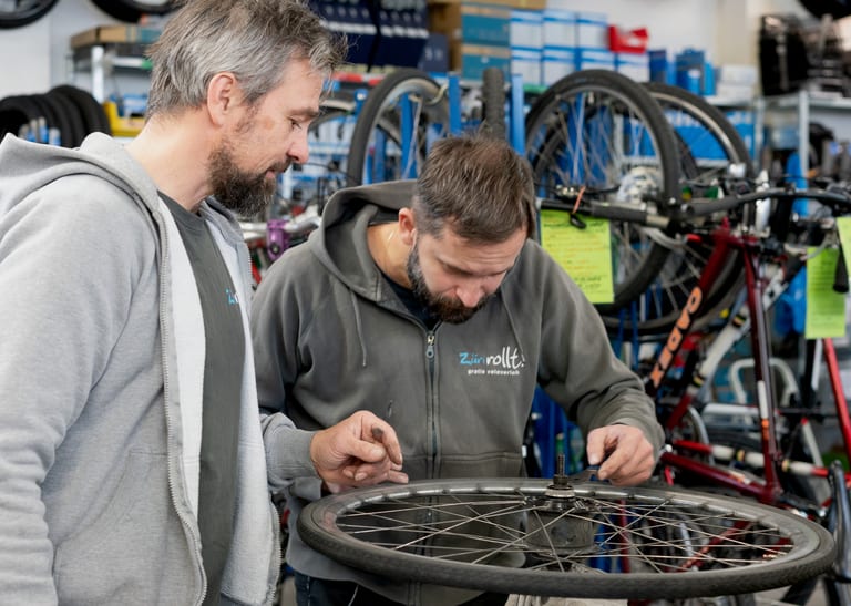 Zwei Menschen reparieren ein Fahrradpneu.