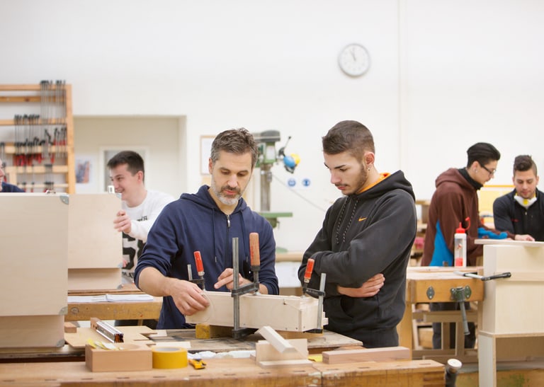 Zwei Menschen arbeiten in einer Holzwerkstatt. 