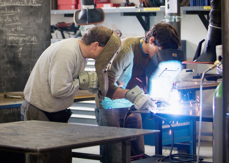 Zwei Mitarbeitende arbeiten in einer Schlosserei.