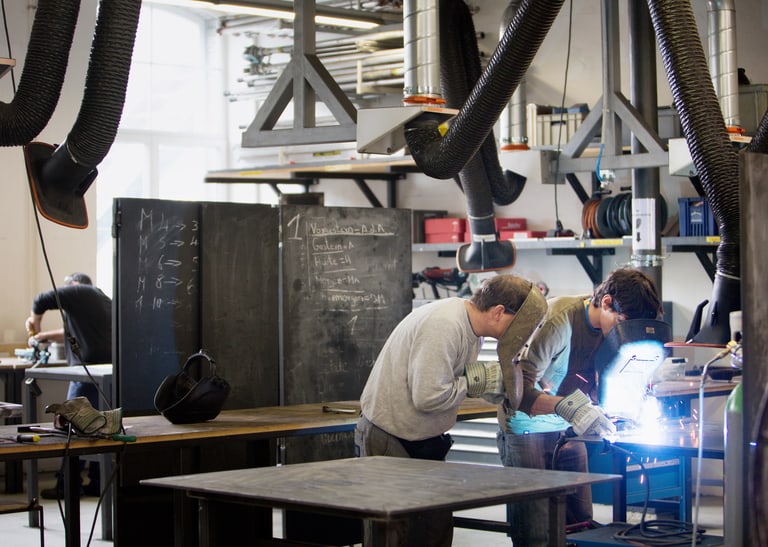 Zwei Mitarbeitende schweissen in einer Schlosserei.