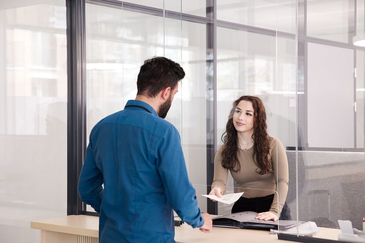 Eine Mitarbeiterin arbeitet beim Empfang.