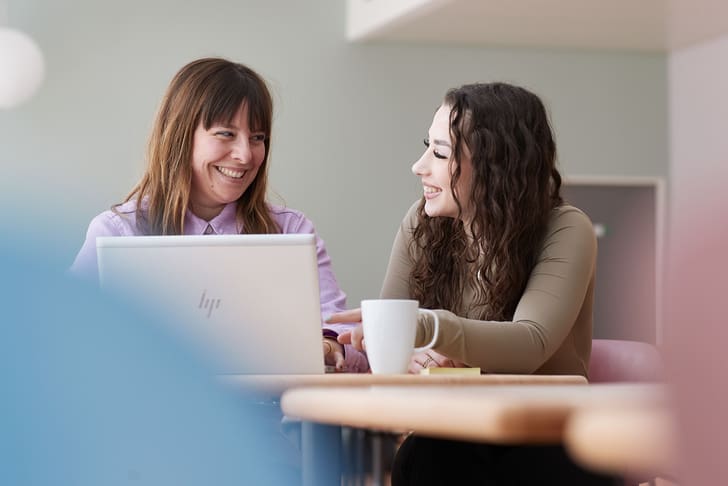 Zwei Mitarbeitende sitzen vor einem Laptop.